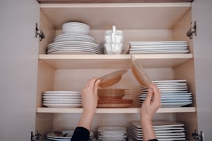 a person is reaching for a plate in a cabinet