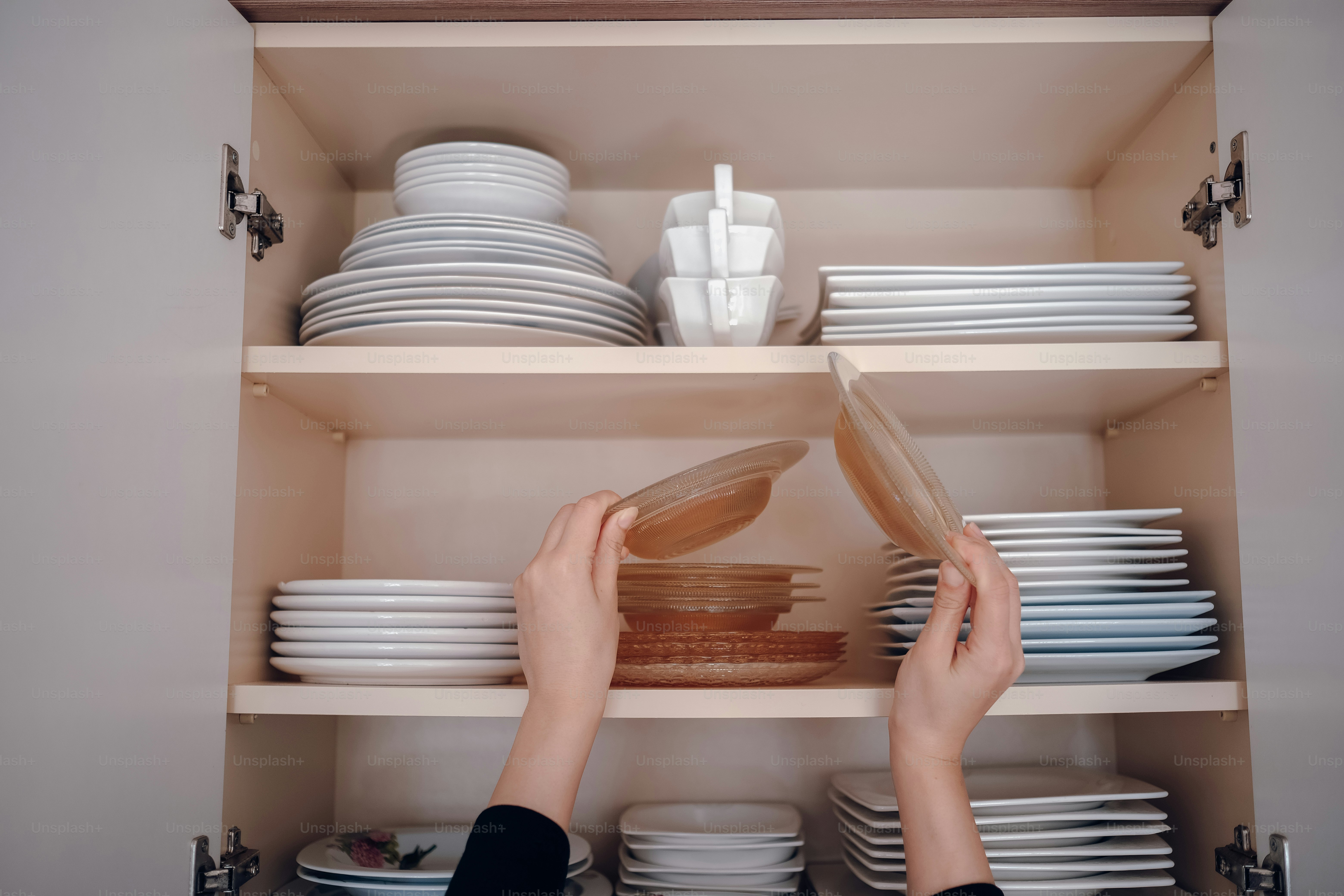 a person is reaching for a plate in a cabinet