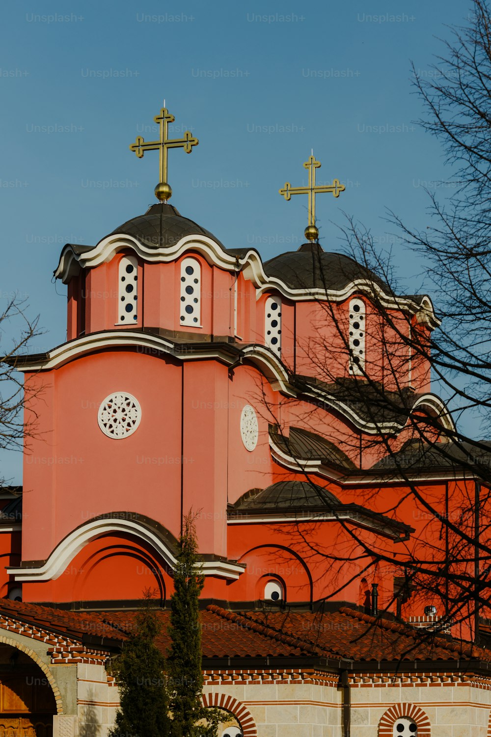 eine rosa Kirche mit drei Kreuzen darauf
