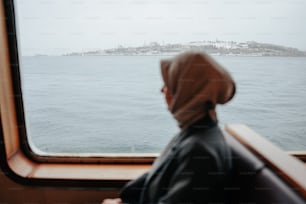 a person looking out a window at the water