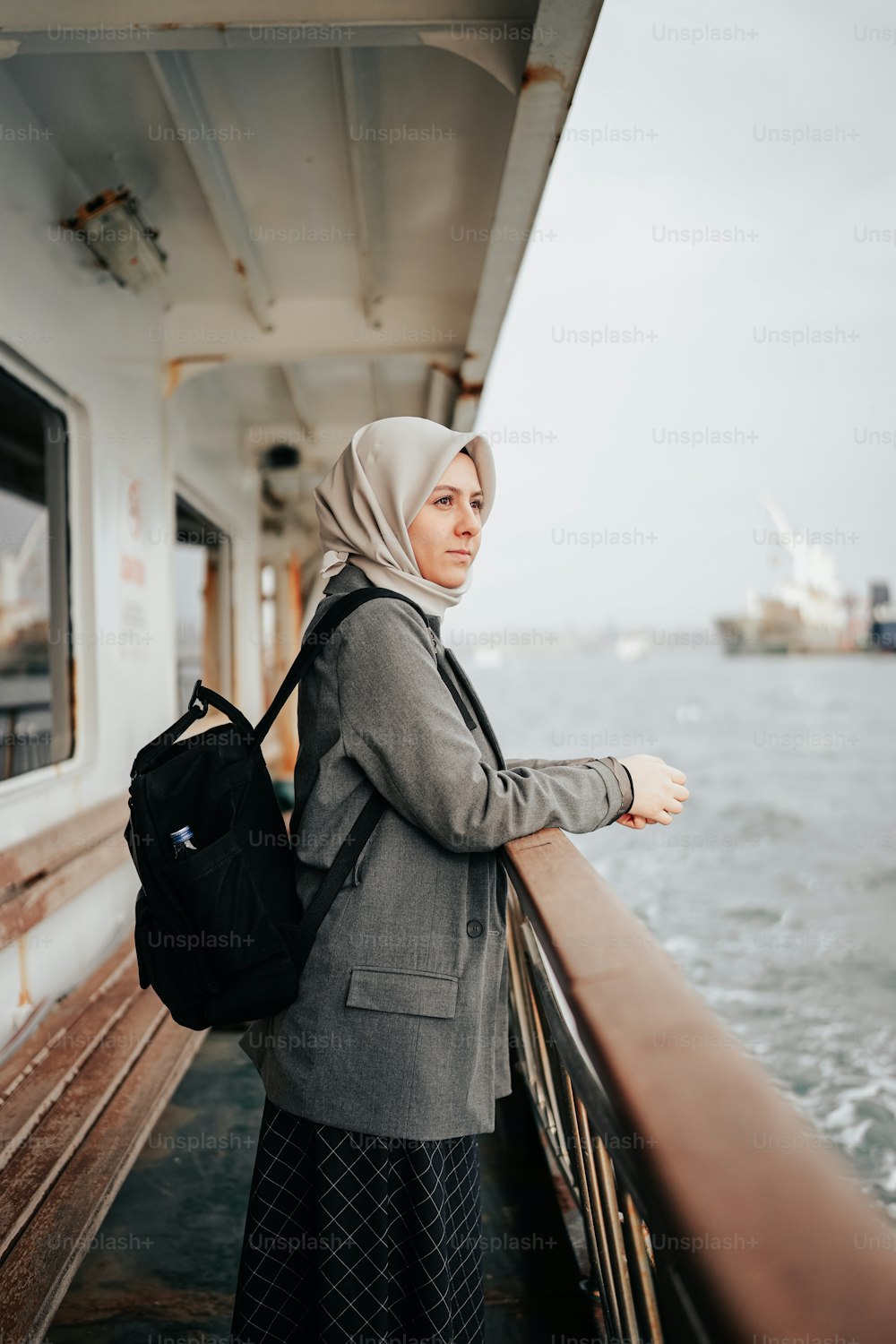 uma mulher em um hijab está de pé em um barco