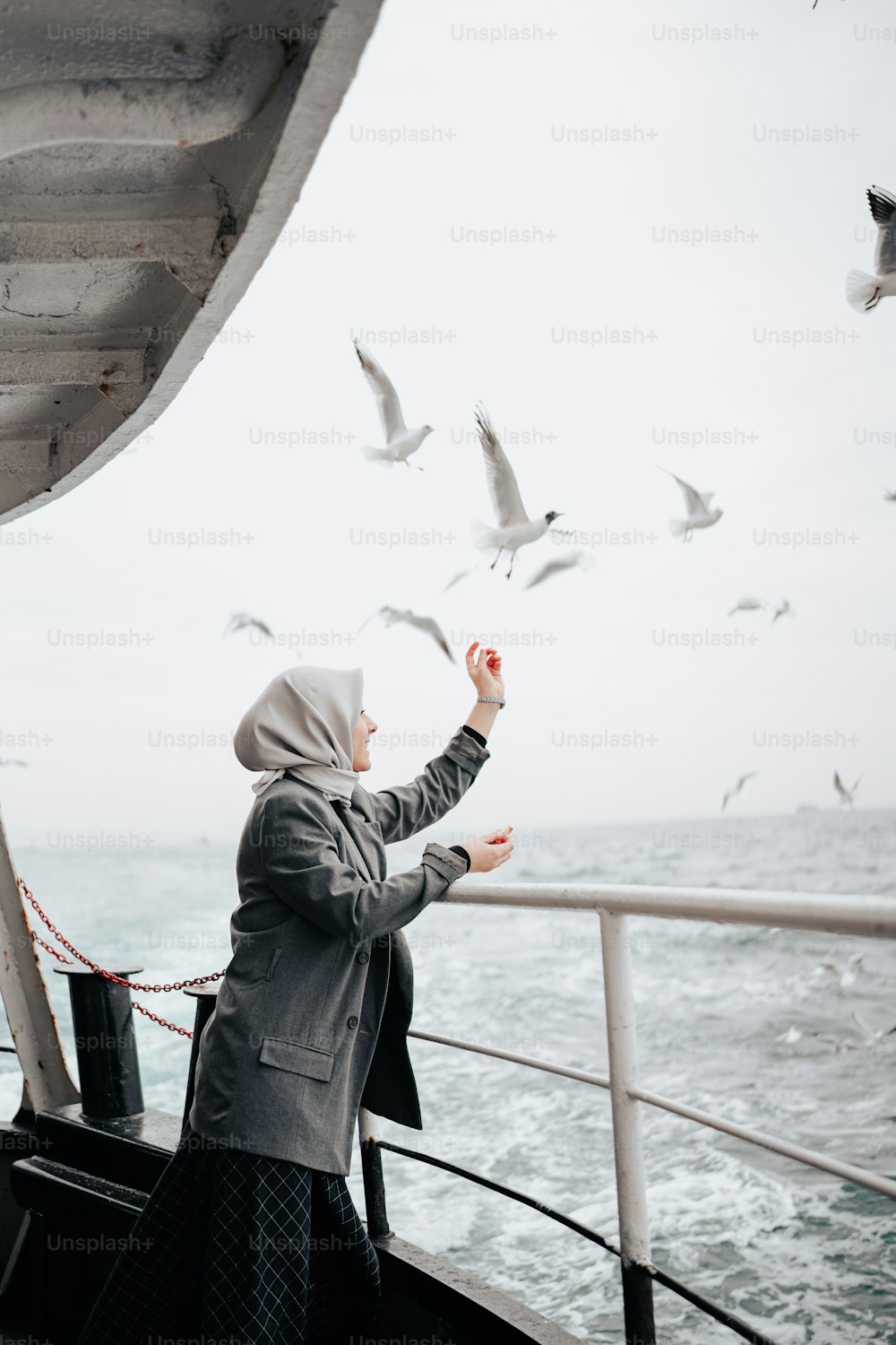 a woman standing on a boat feeding seagulls