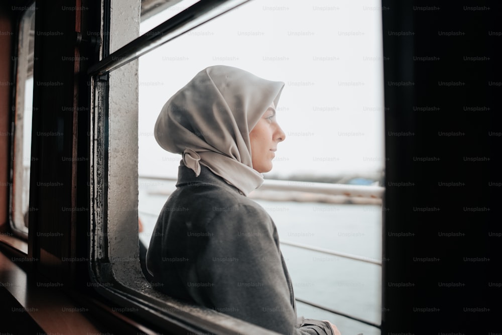 a woman looking out a window at the water