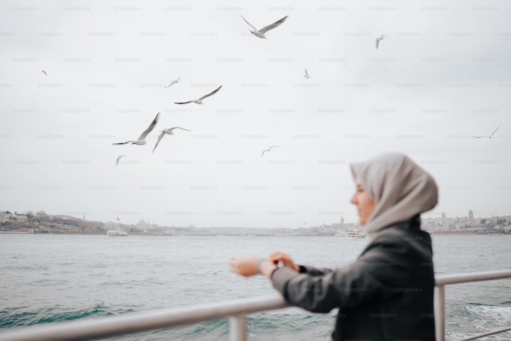 uma mulher de pé em um barco olhando para gaivotas