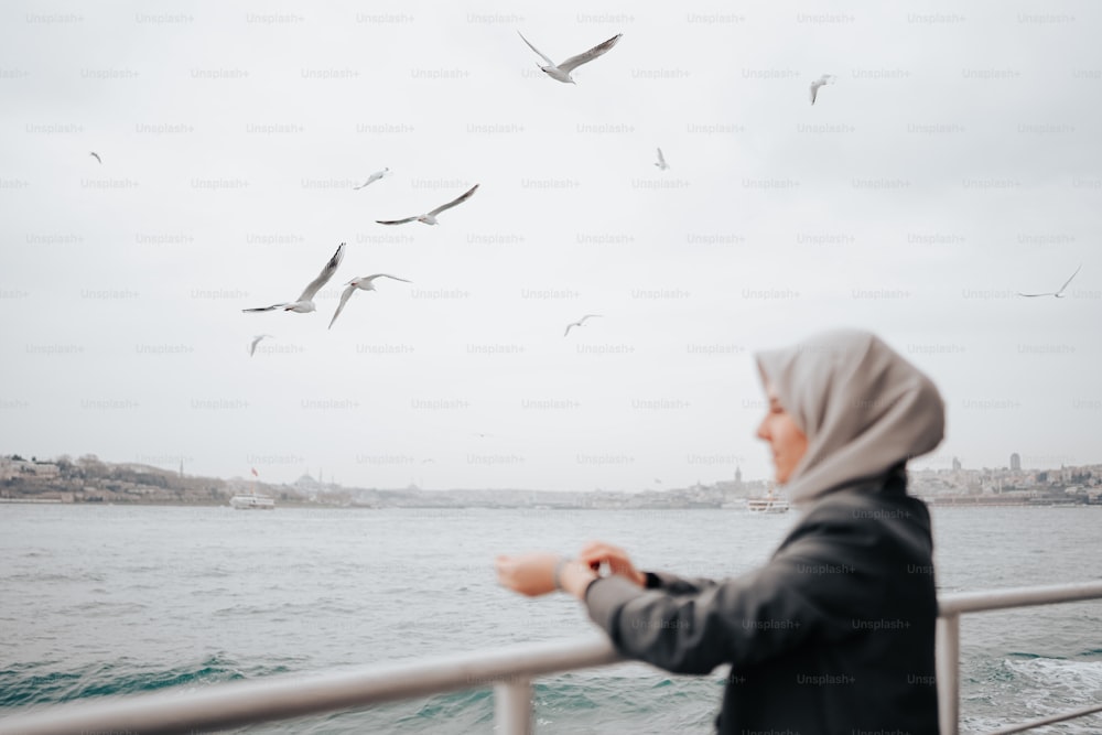 a woman standing on a boat looking at seagulls