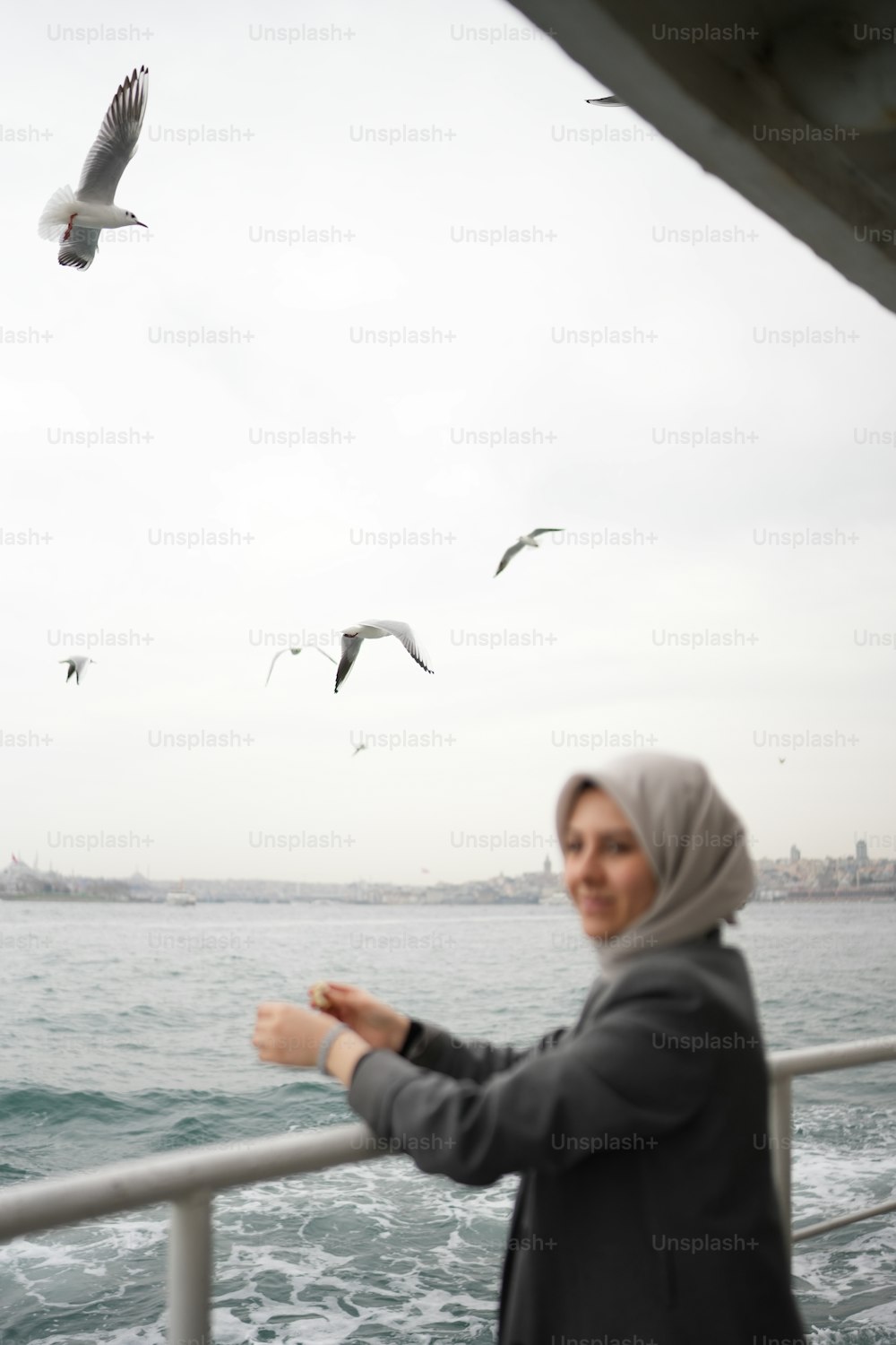 Eine Frau, die auf einem Boot steht und Möwen betrachtet