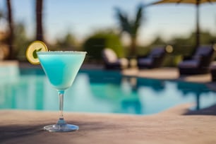 a blue cocktail sitting next to a swimming pool