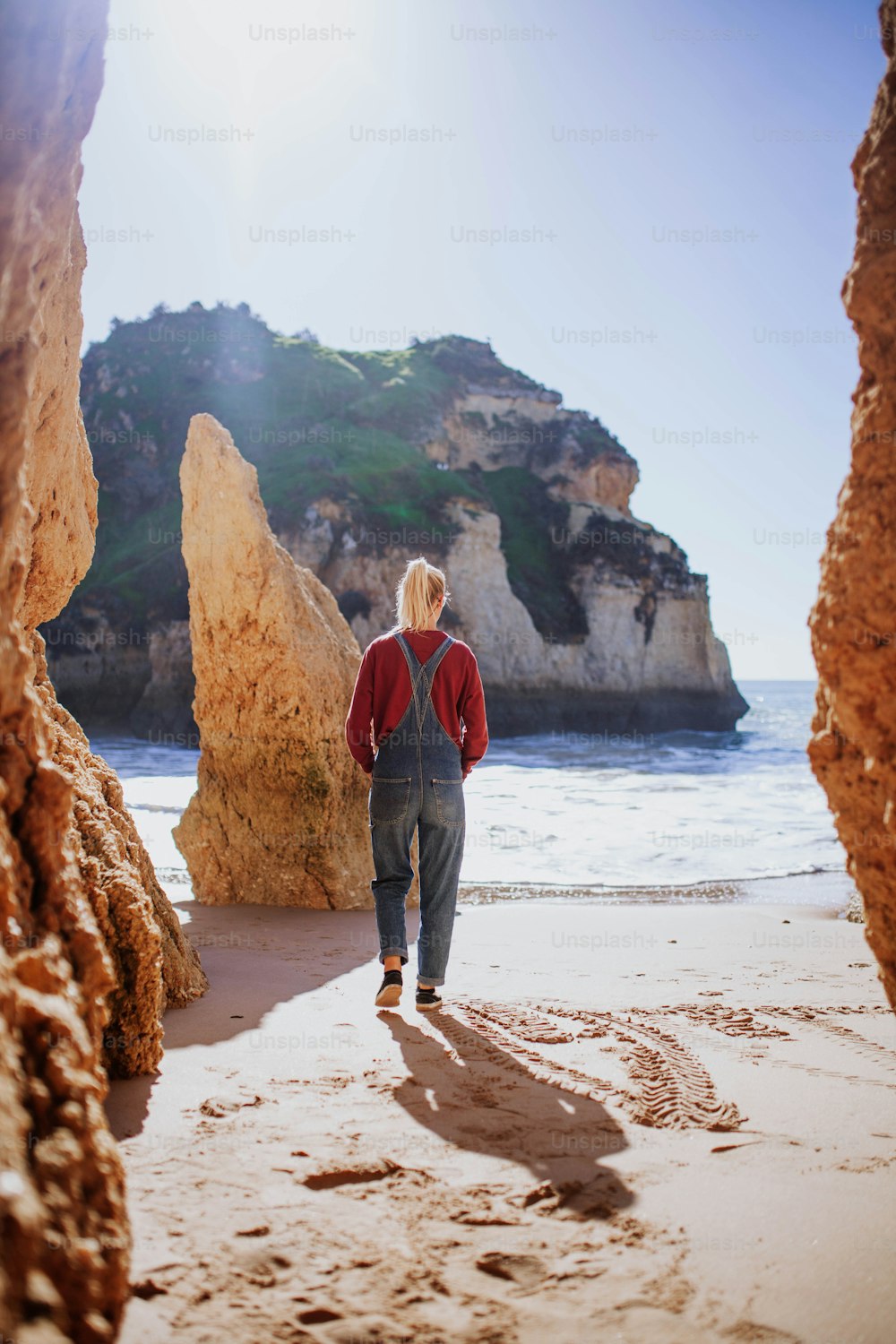 a person walking on a beach near some rocks