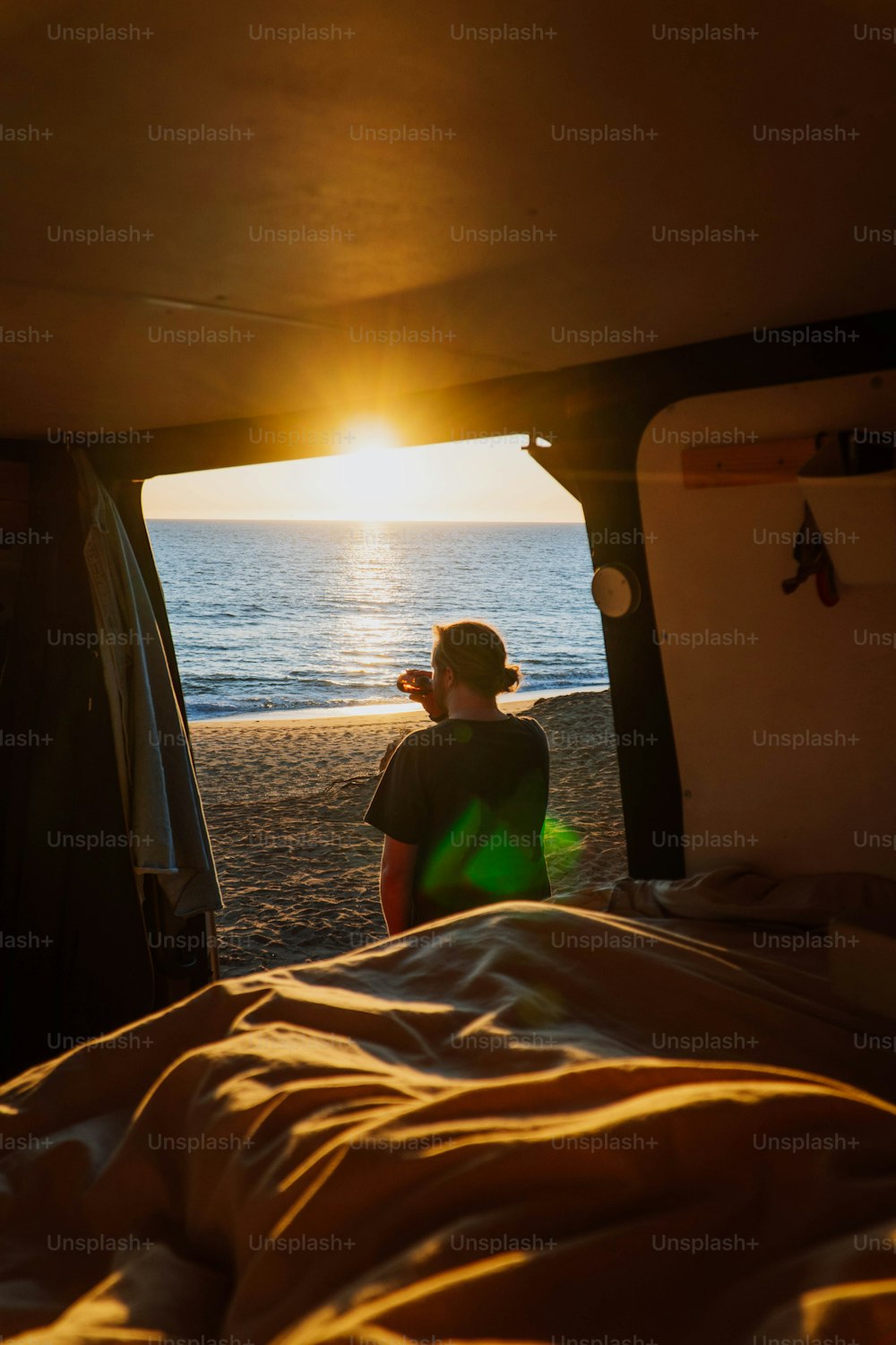 a person standing in the back of a truck on a beach