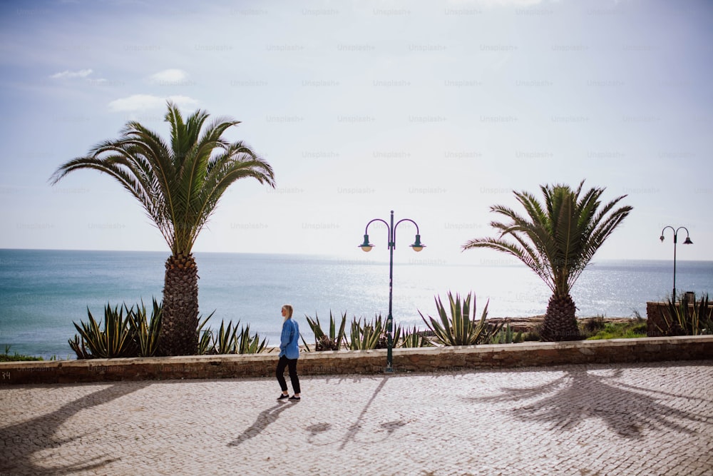 um homem andando de skate por uma calçada ao lado do oceano