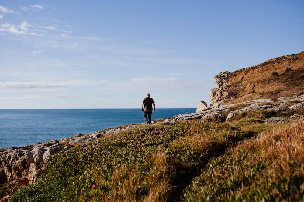 um homem de pé em um penhasco com vista para o oceano