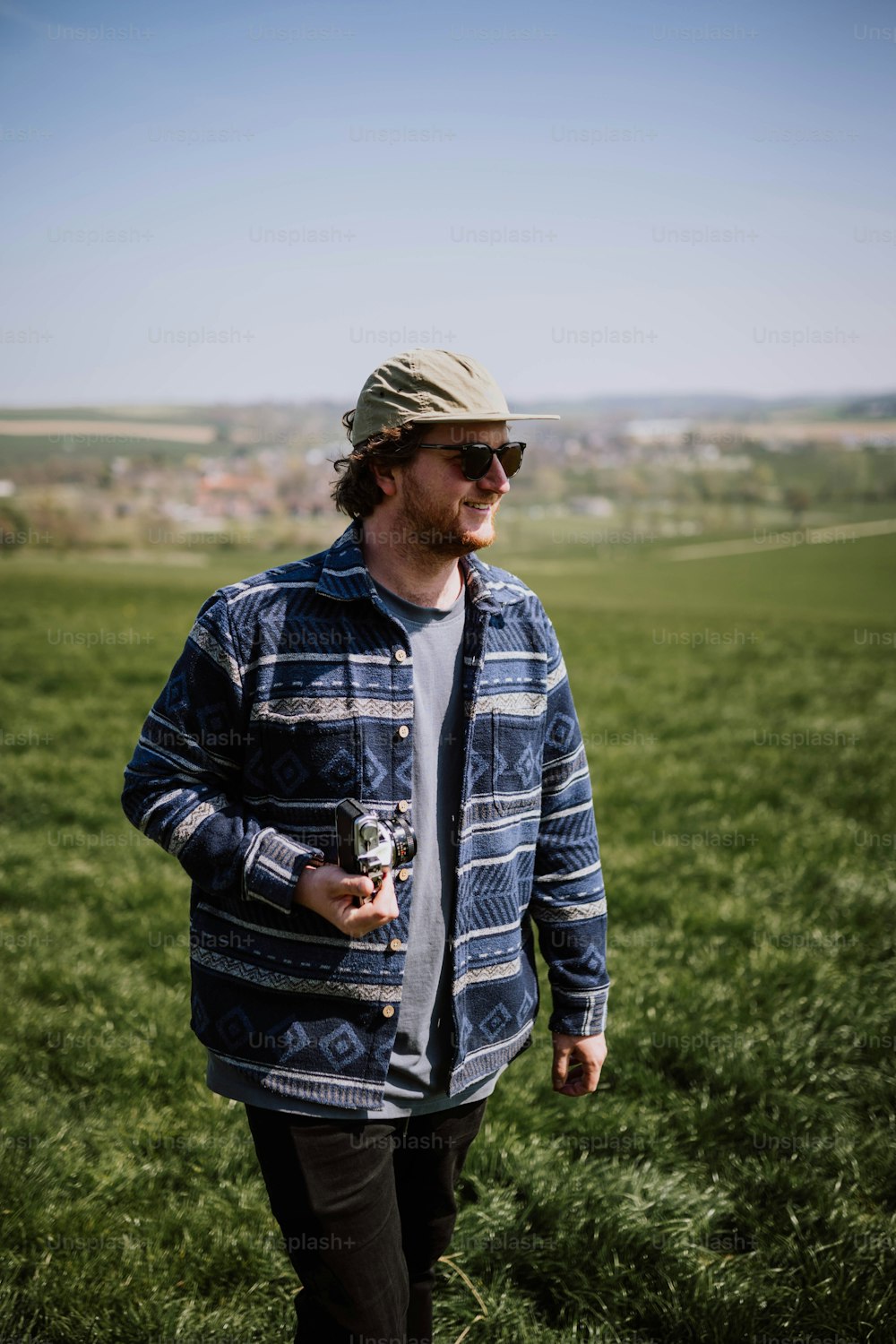 um homem de pé em um campo com uma cerveja na mão