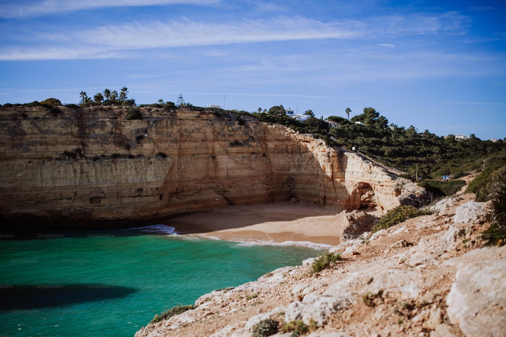 a rocky cliff overlooks the ocean and a sandy beach
