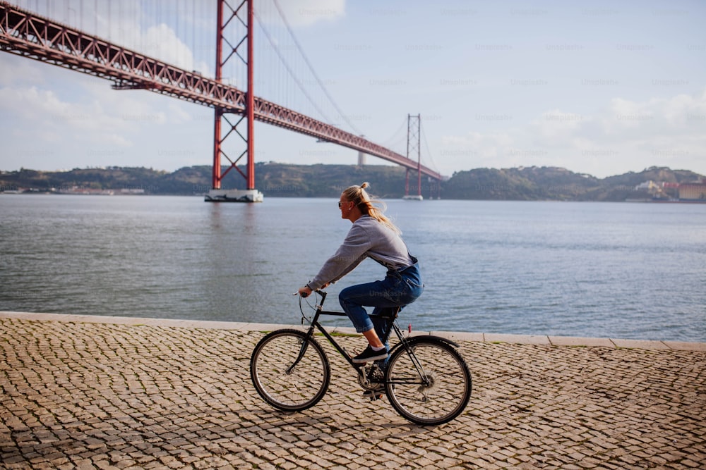 a woman is riding a bike by the water