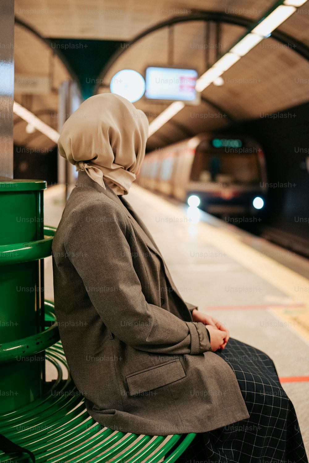 a woman sitting on a bench in a subway station