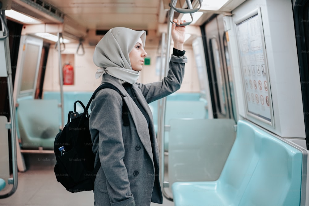 uma mulher em um hijab está de pé em um trem