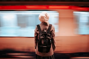 a woman with a backpack standing in front of a train