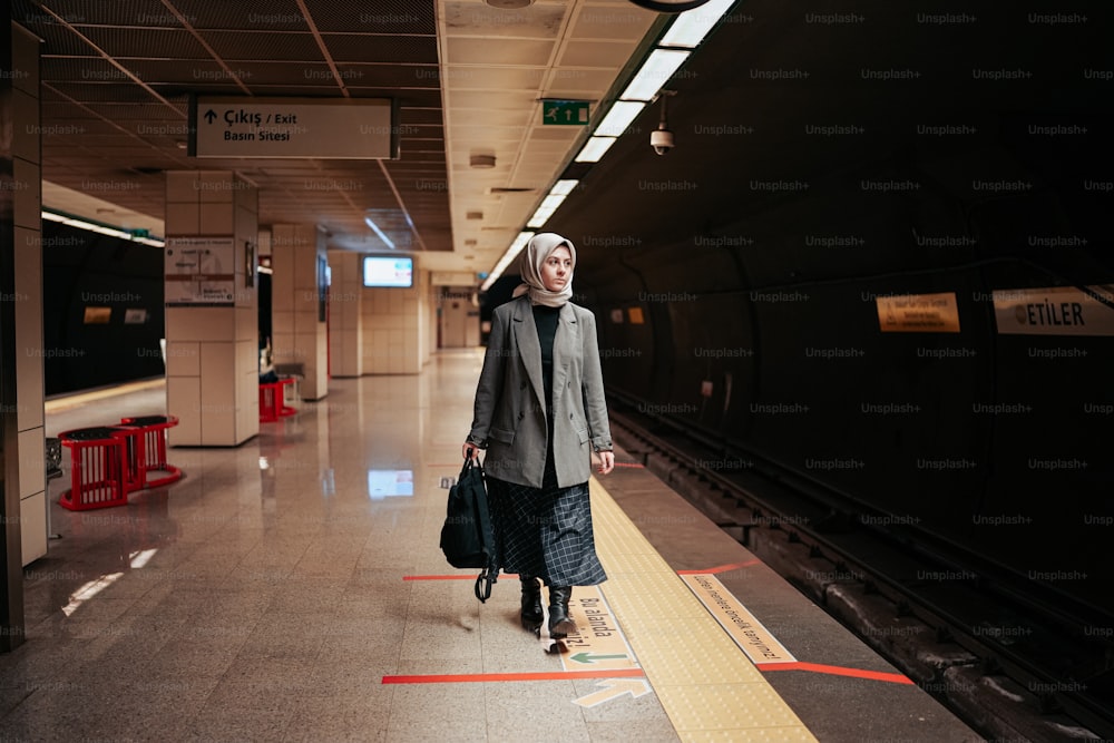a woman walking down a train platform with a suitcase