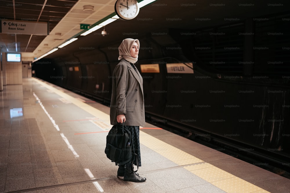 uma mulher em um hijab em pé em uma estação de trem