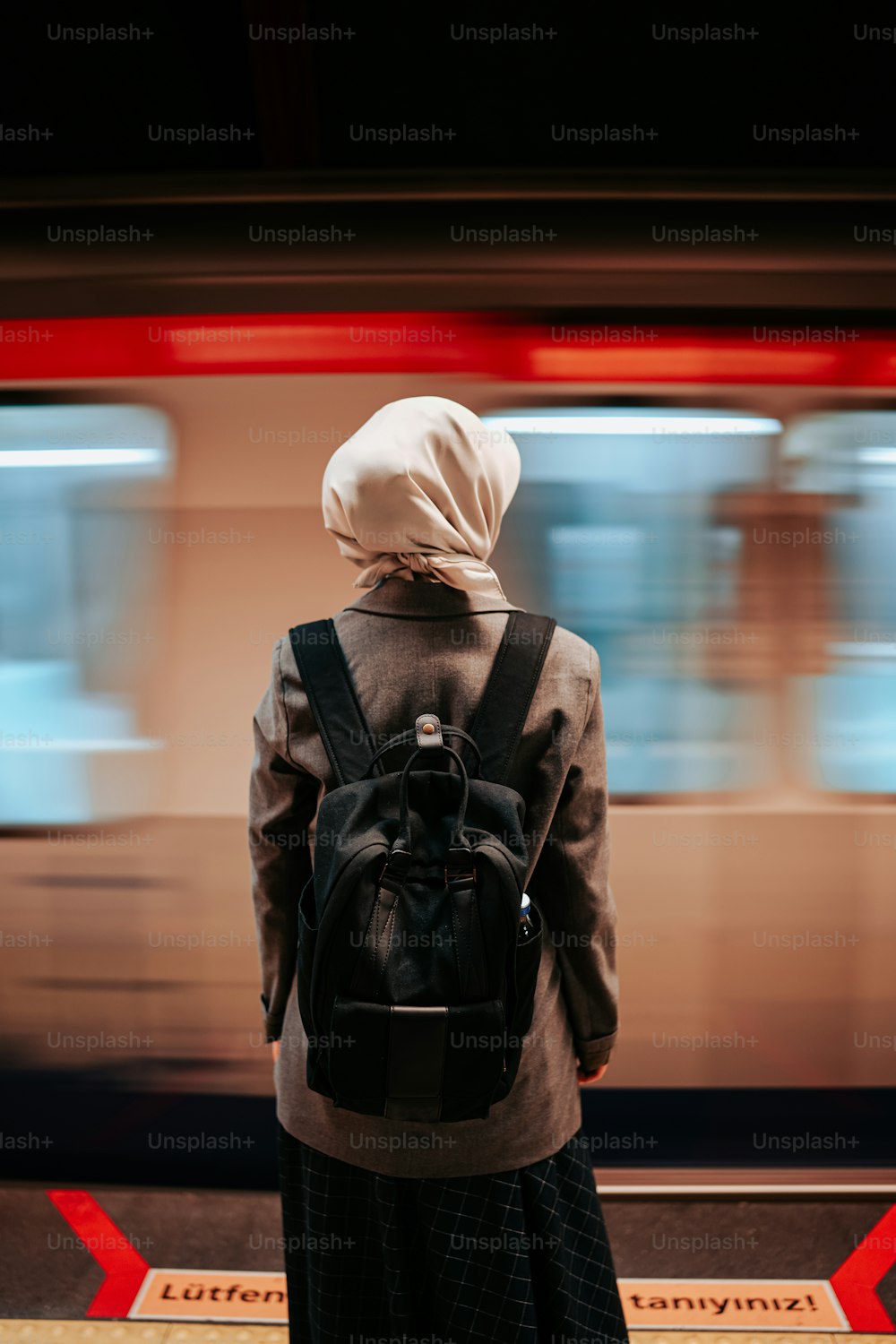 a person with a backpack standing in front of a train