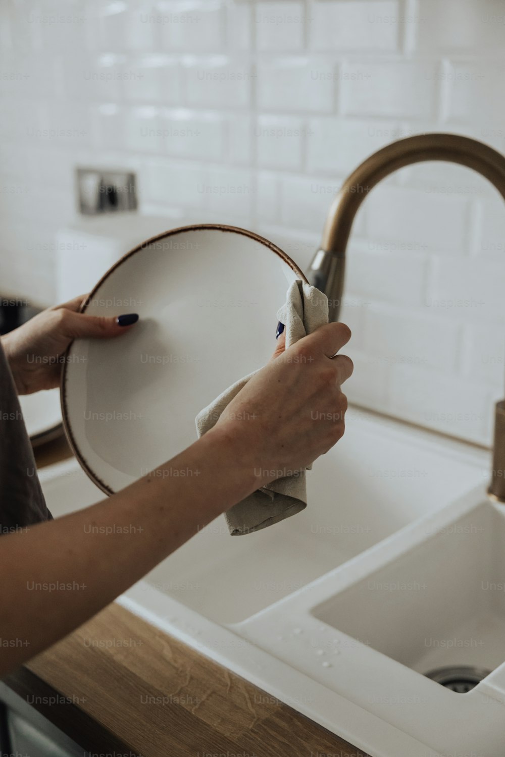 a woman is cleaning a kitchen sink with a rag