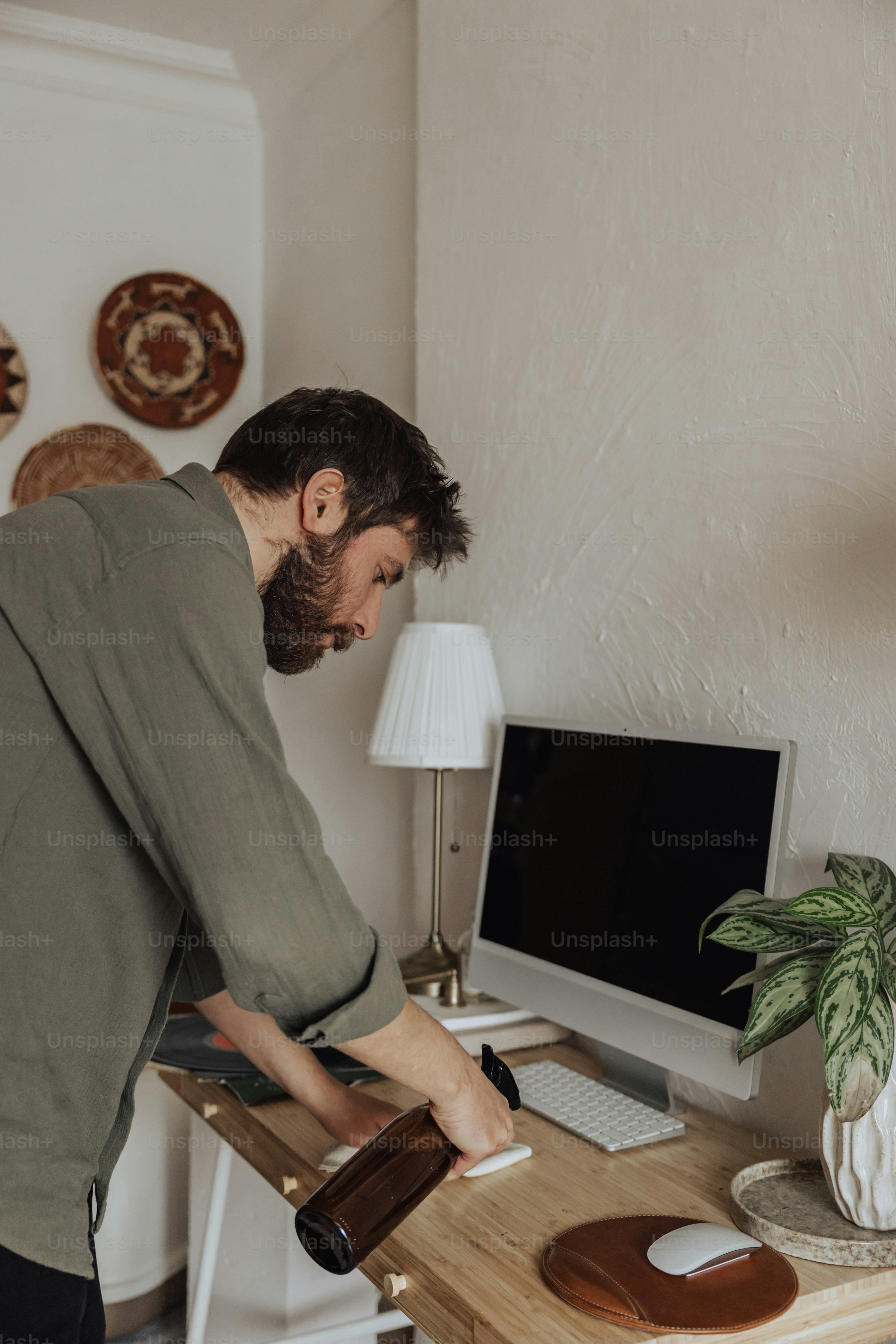 a man standing over a wooden desk with a computer on it