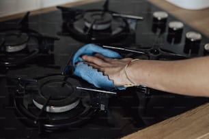 Una persona limpiando una estufa con un paño azul