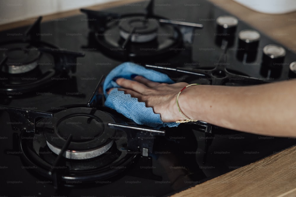 a person cleaning a stove with a blue cloth