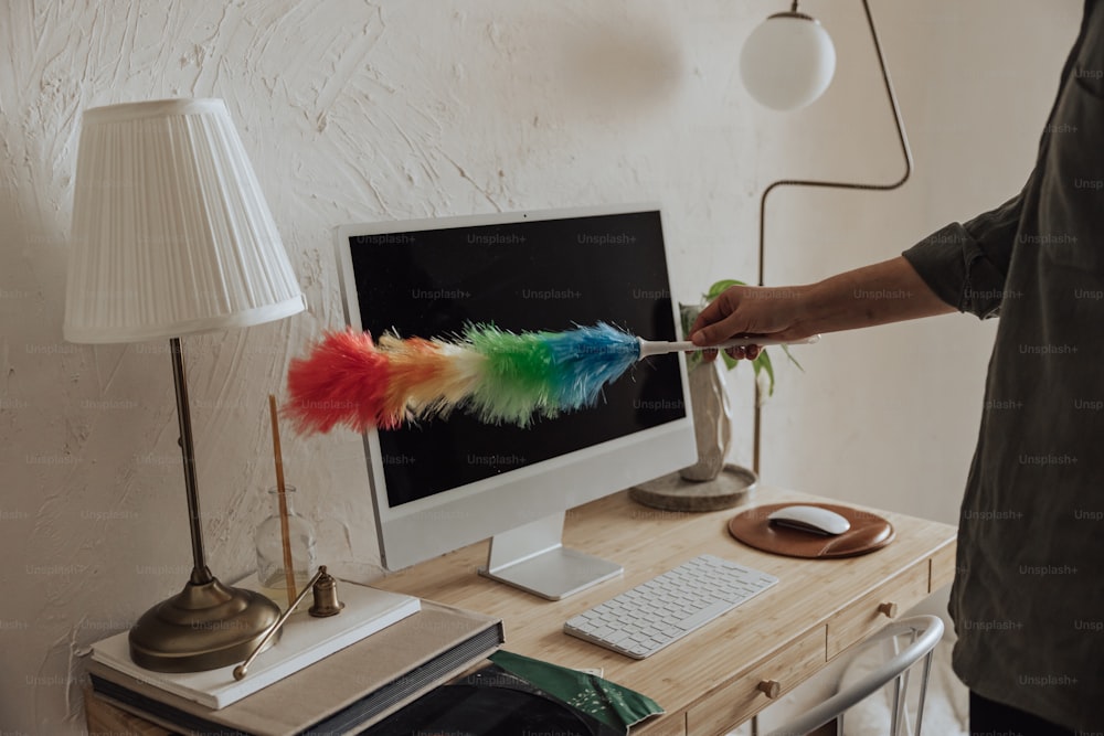 Une personne tient une plume colorée sur un ordinateur