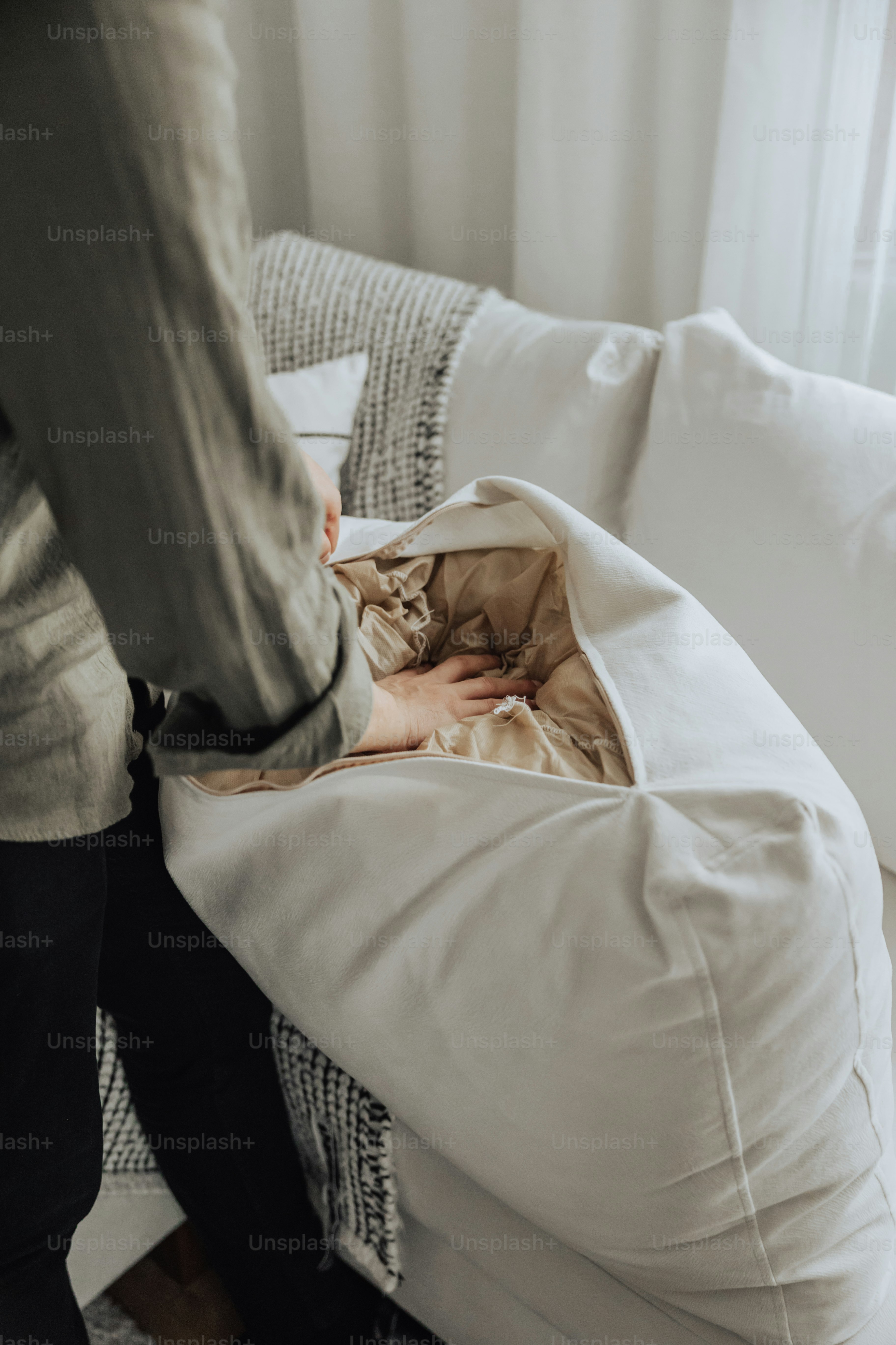 A person standing on a bed with a white comforter photo Cleaning
