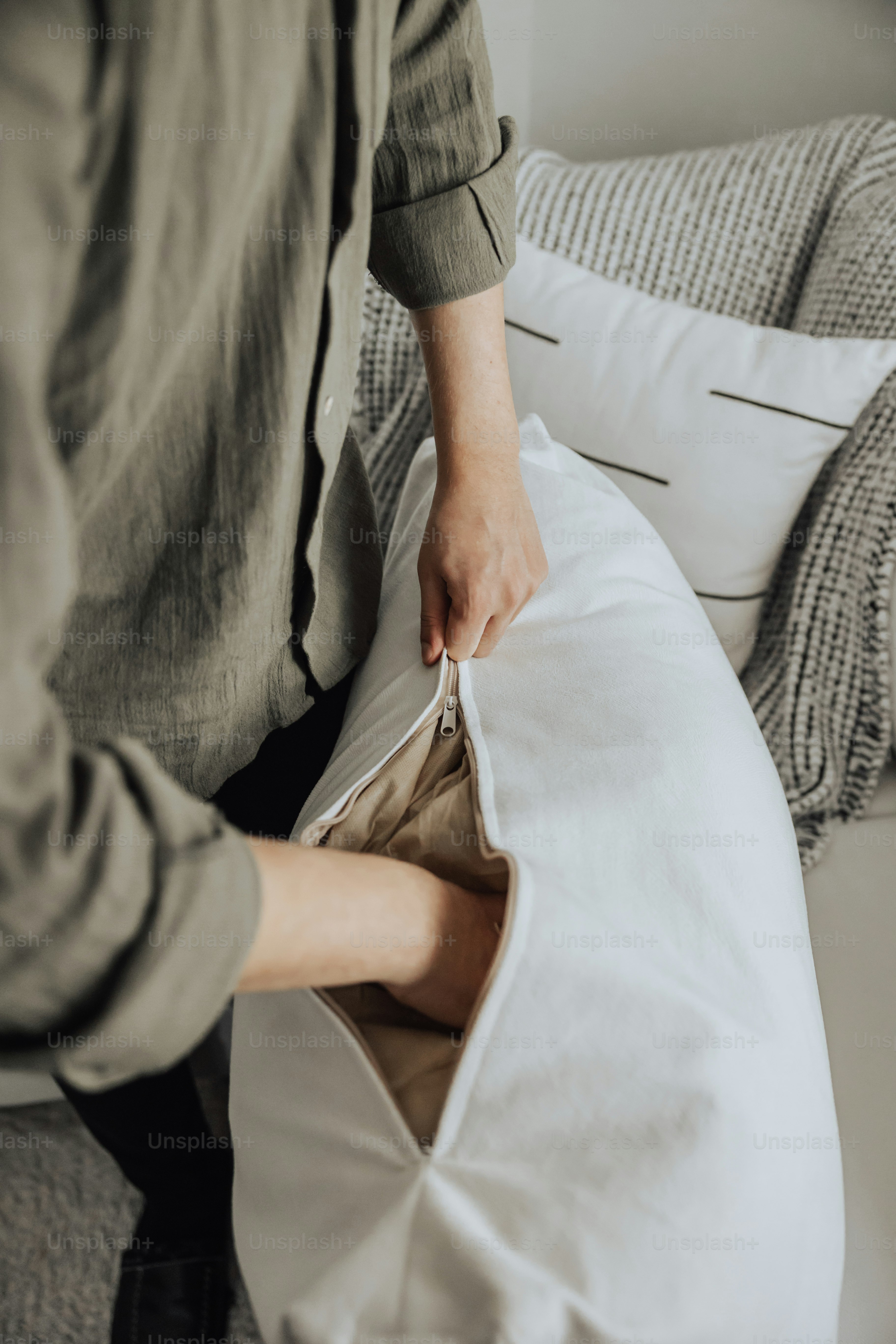 A person opening up a pillow on a couch photo Cushion Image on Unsplash