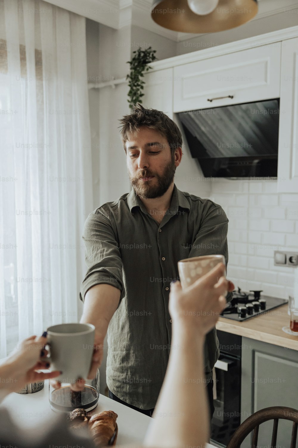um homem segurando uma xícara de café enquanto está ao lado de uma mulher