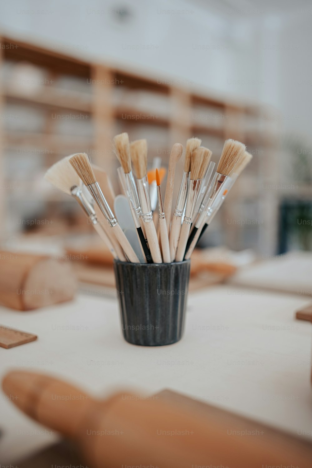 a cup filled with lots of brushes on top of a table