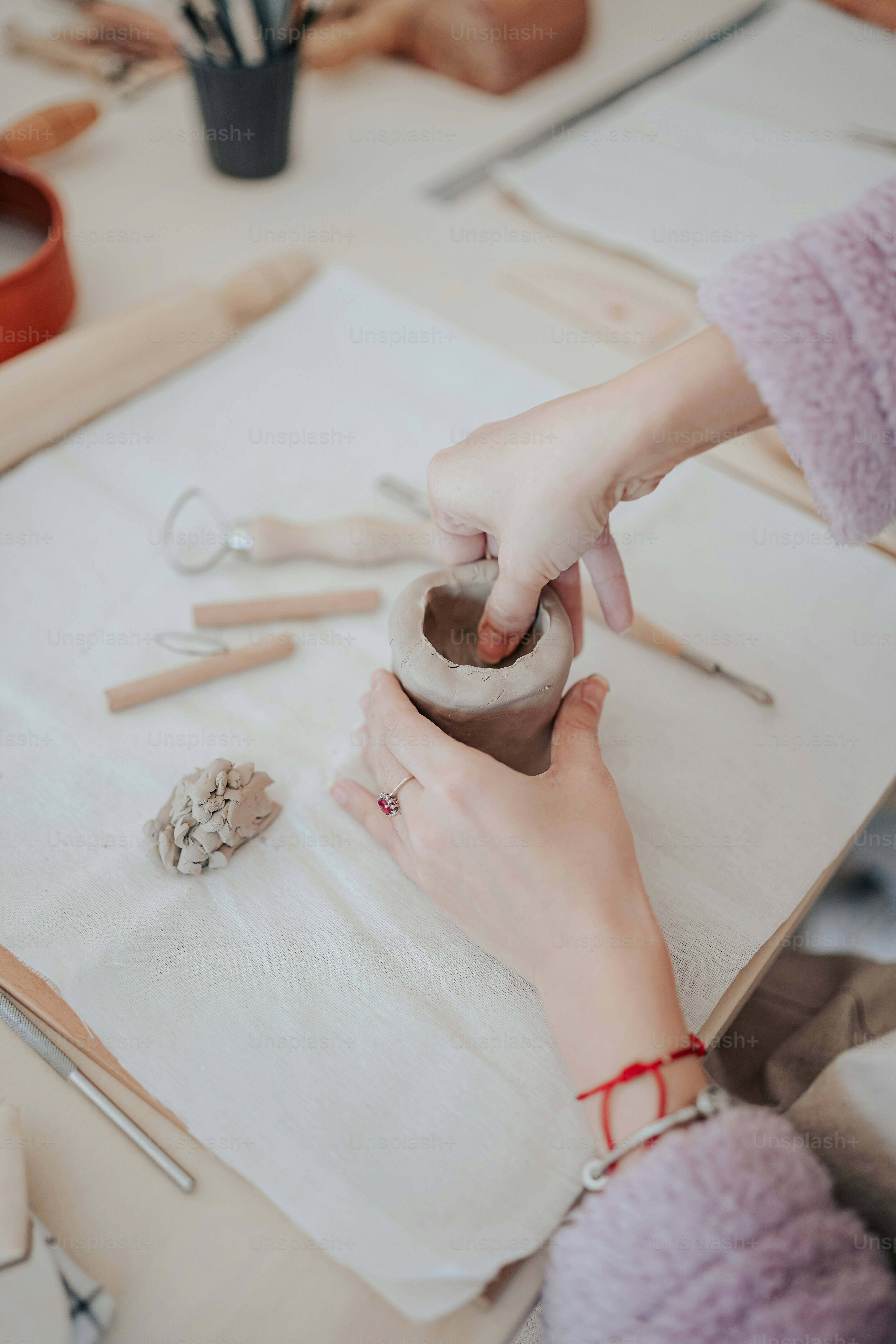 한 여자가 점토로 꽃병을 만들고 있다