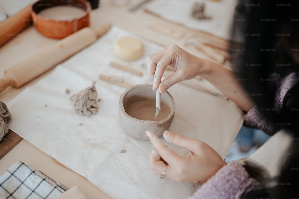 a woman is making a clay bowl on a table
