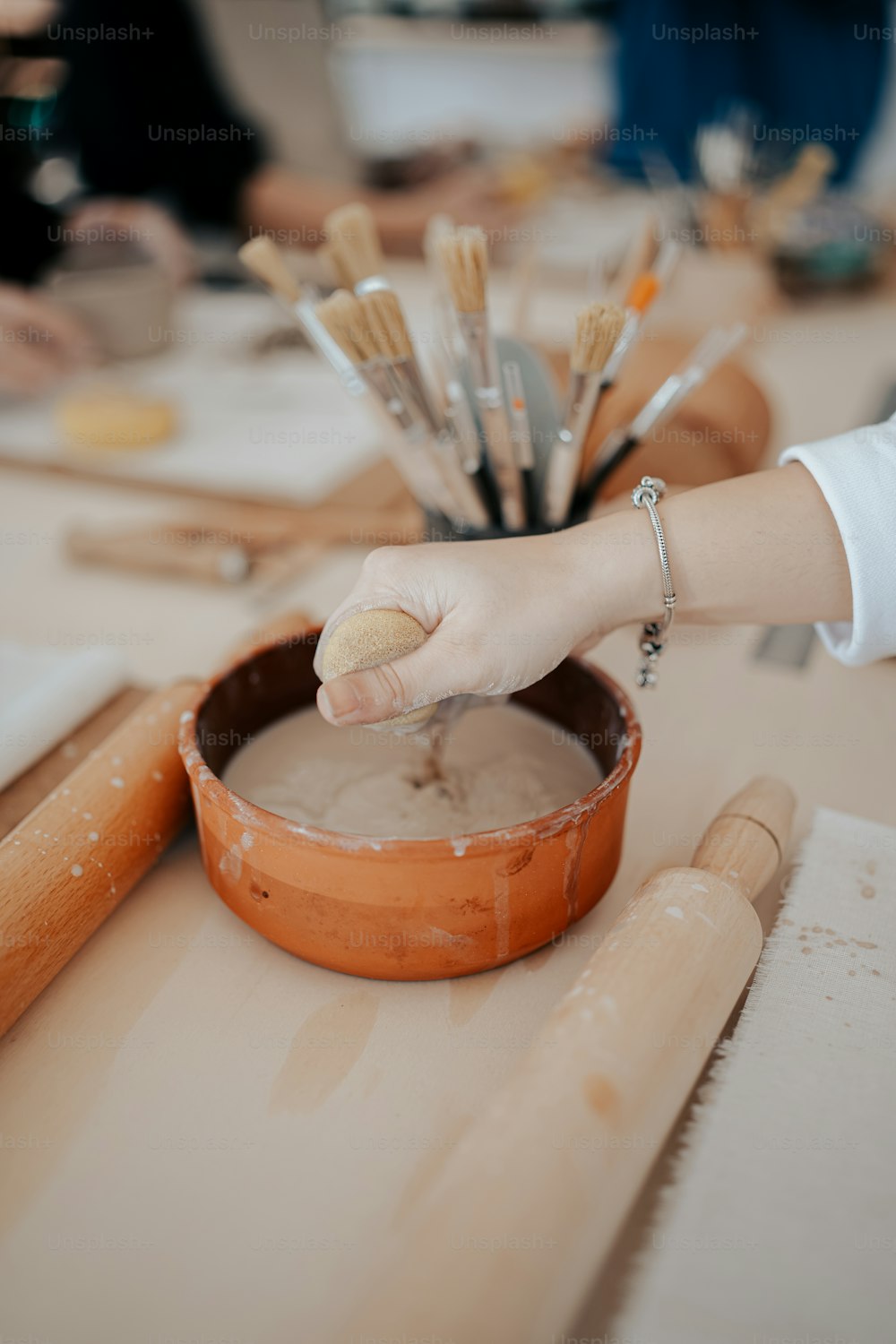a person is painting a bowl with paintbrushes