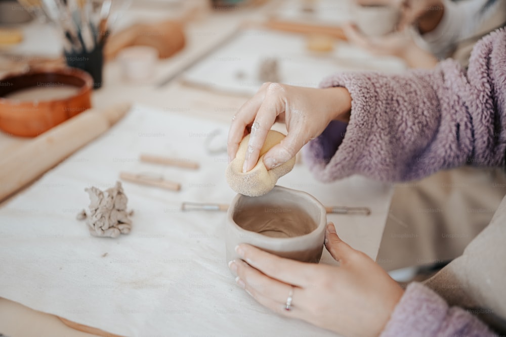 a woman is making something out of clay