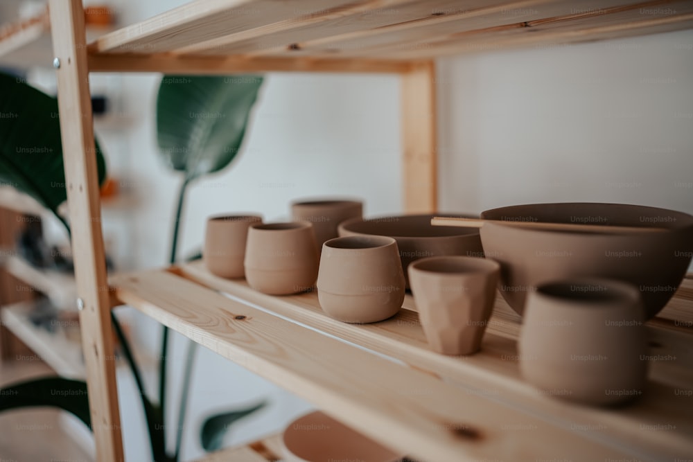 a shelf filled with pots and bowls on top of a wooden shelf