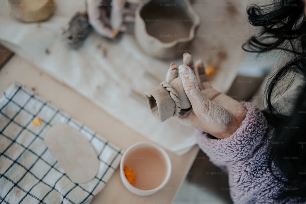 a woman is holding a piece of clay in her hands