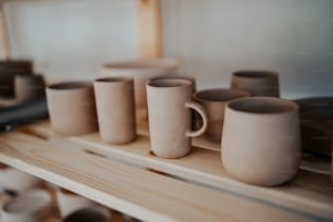 une rangée de tasses à café posées sur une étagère en bois