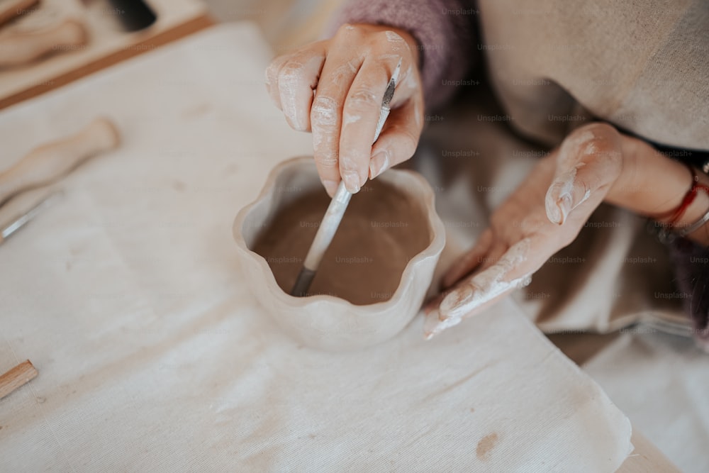 a woman is making a vase out of clay