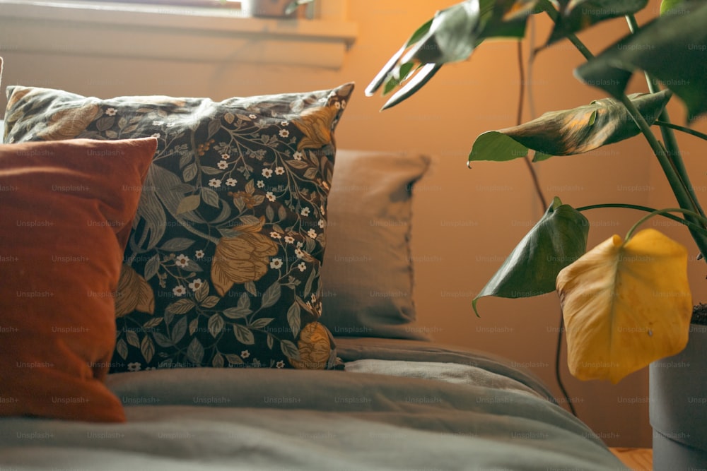 Una cama cubierta con muchas almohadas al lado de una planta
