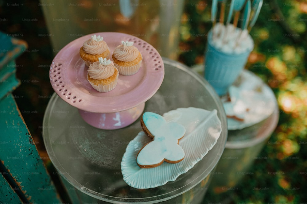 a table topped with cupcakes and cookies on top of plates