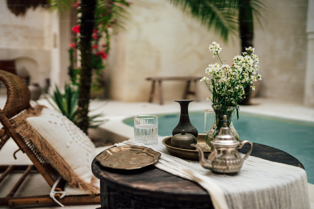 ein Tisch mit einer Vase Blumen darauf neben einem Pool