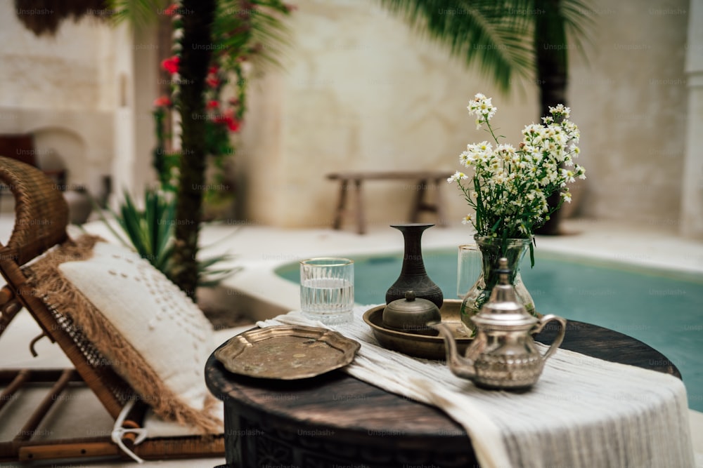 una mesa con un jarrón de flores junto a una piscina