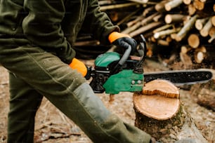 uma pessoa usando uma motosserra para cortar um tronco
