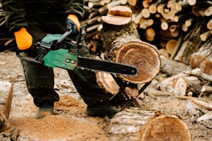 a man holding a chainsaw on top of a pile of logs