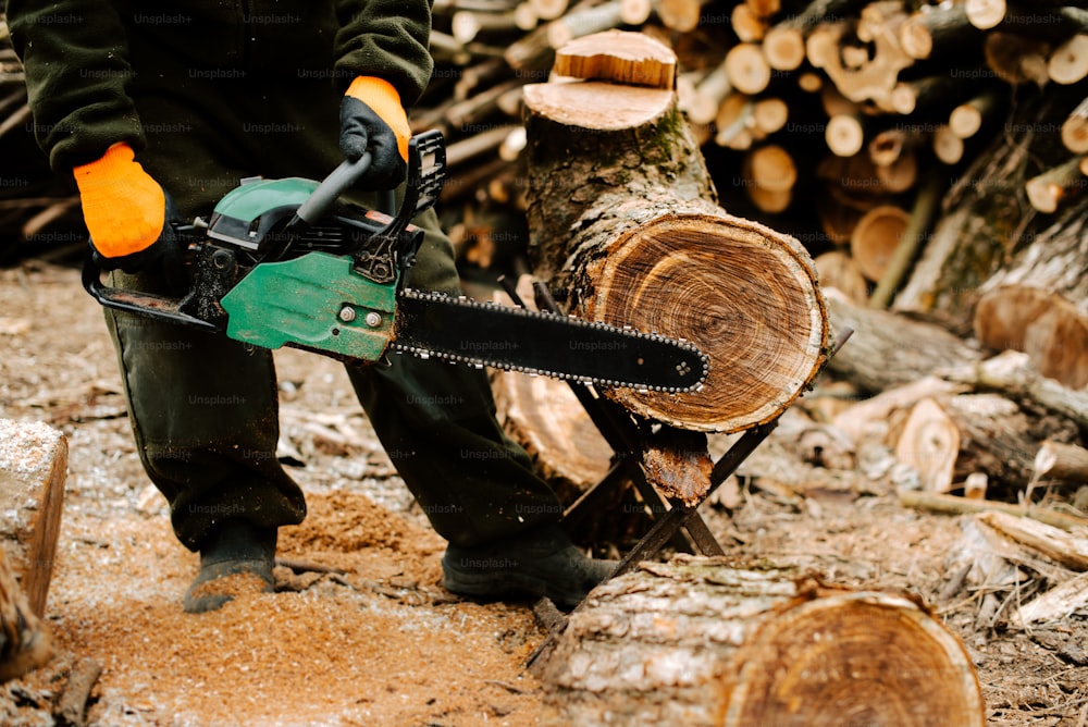 a man holding a chainsaw on top of a pile of logs
