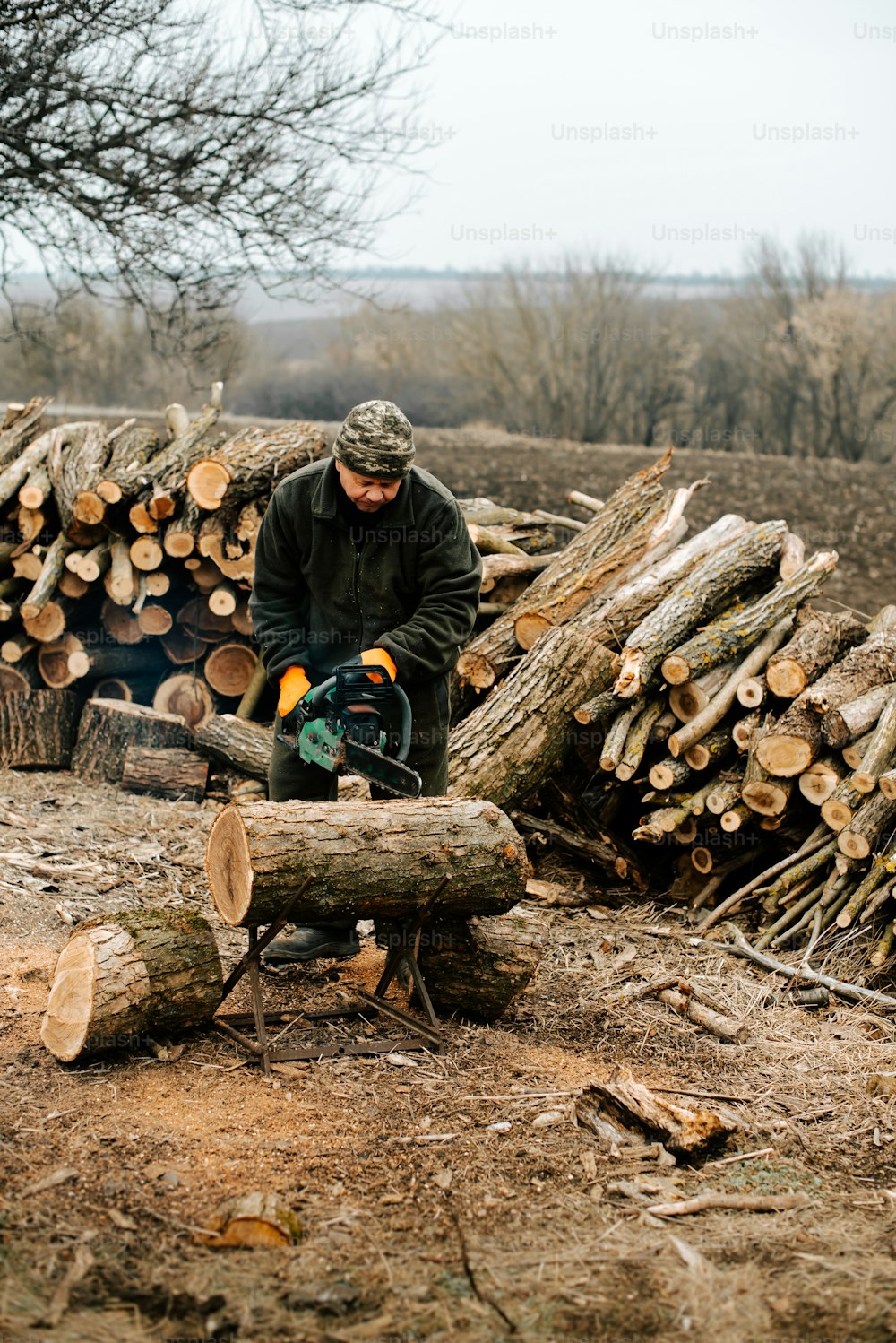 Un homme coupe du bois avec une tronçonneuse