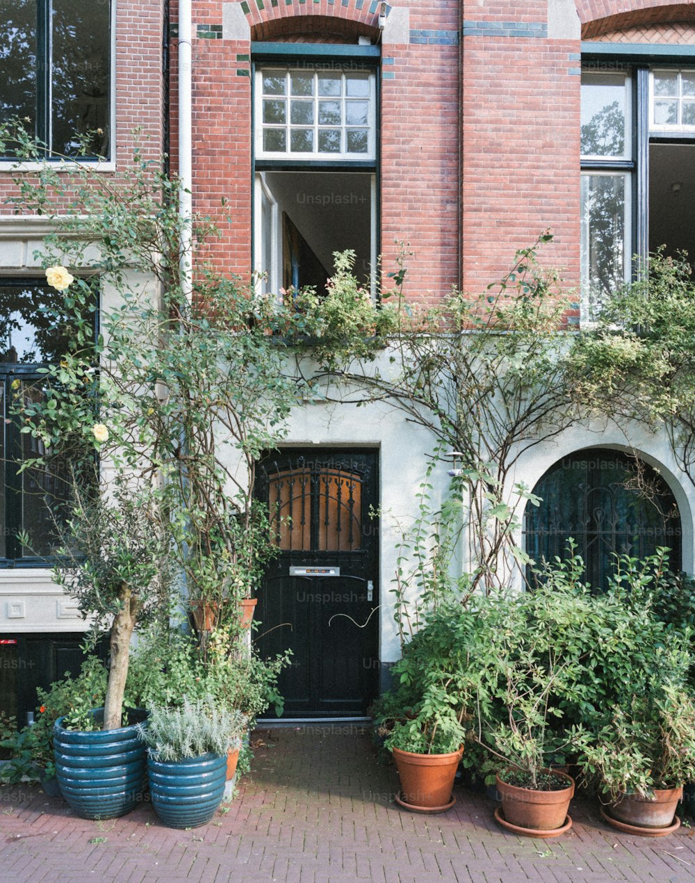 a brick building with potted plants and a black door
